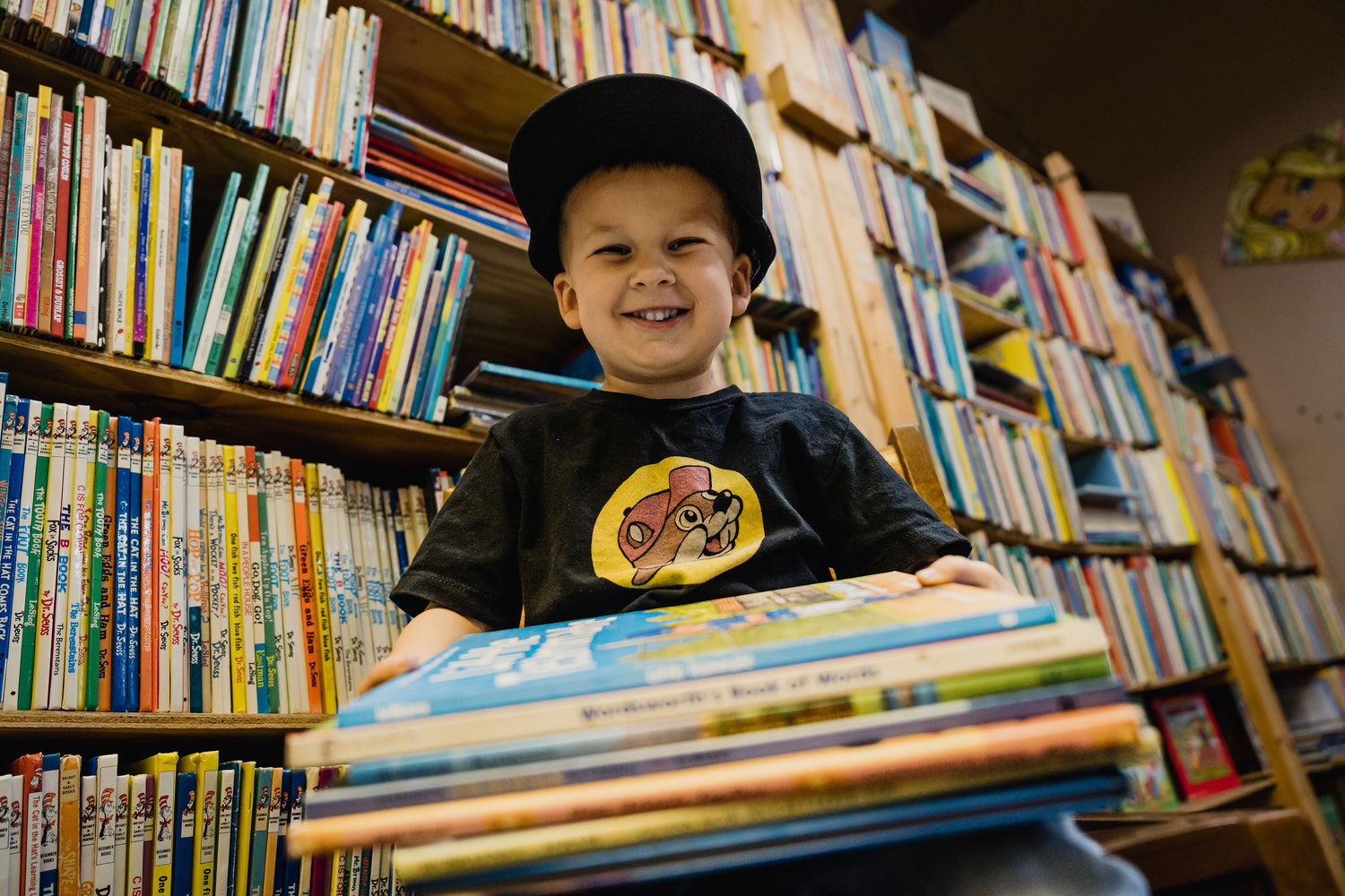 smiling little boy holding a stack of books